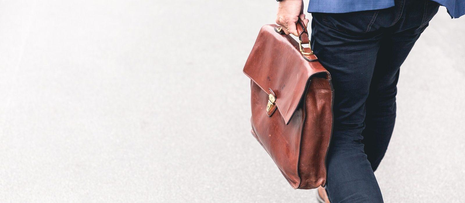 person walking holding brown leather bag