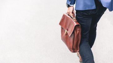 person walking holding brown leather bag